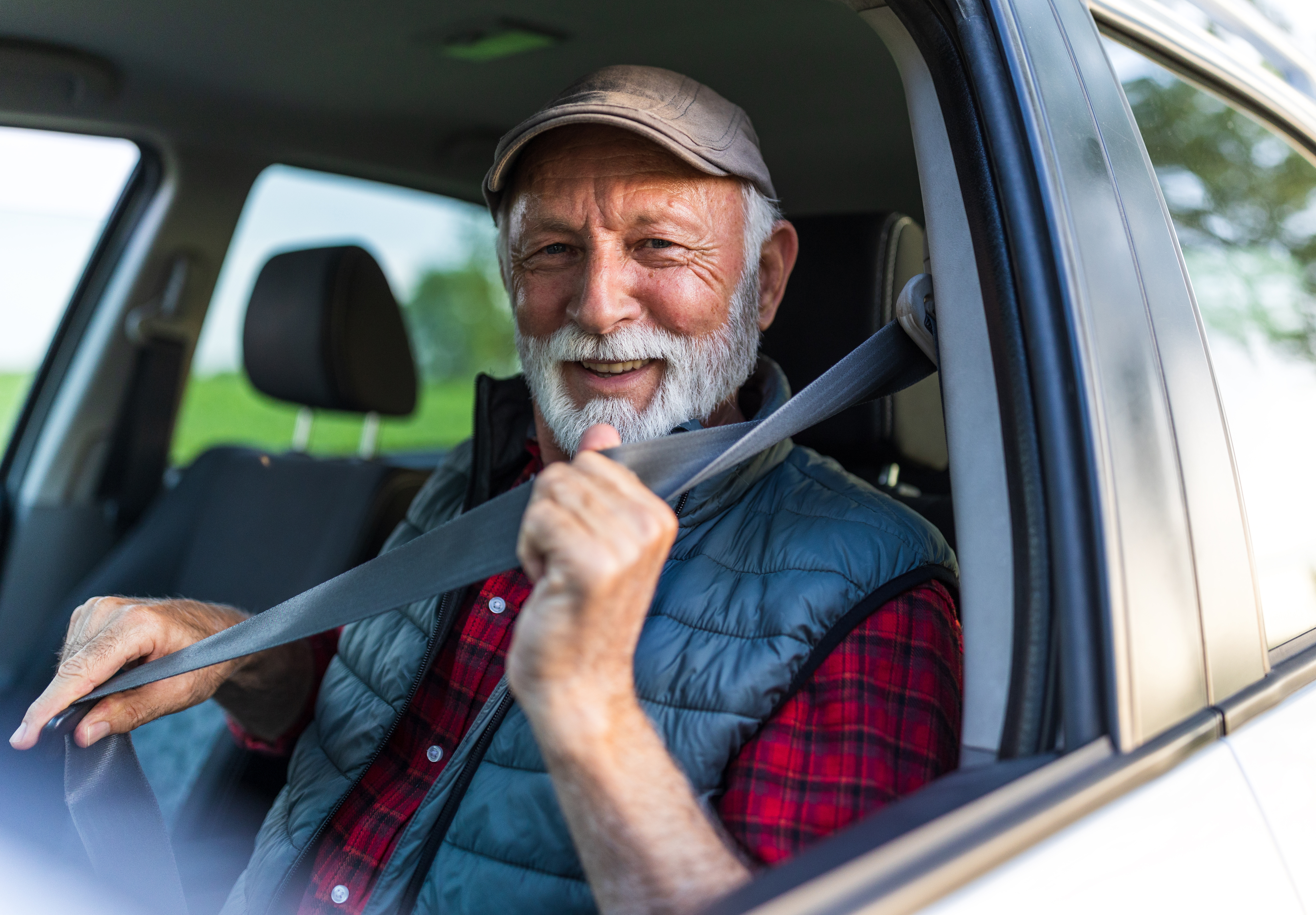 A photo of an older male driver putting on his safety belt.